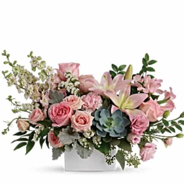 Pink roses and lilies in a white rectangular vase with succulents