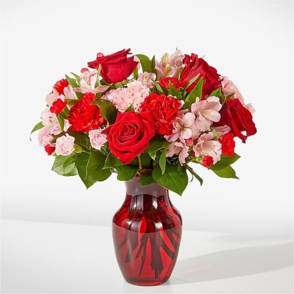 Red roses and pink carnations in a red glass vase