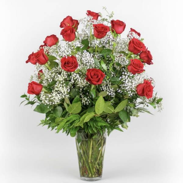 Red roses arranged in a clear glass vase with white filler flowers