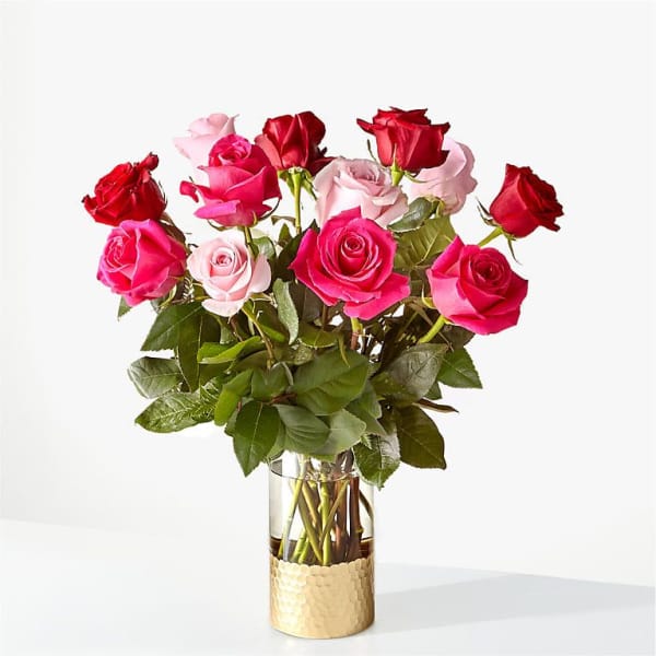 Bouquet of pink and red roses in a glass vase with a gold base