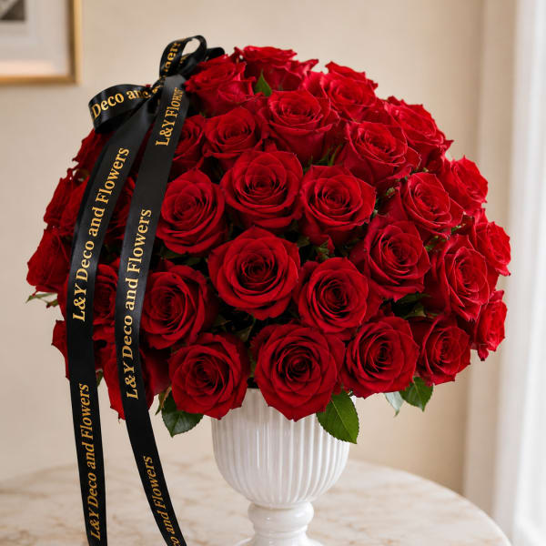 Red rose bouquet in a white pedestal vase with black ribbon
