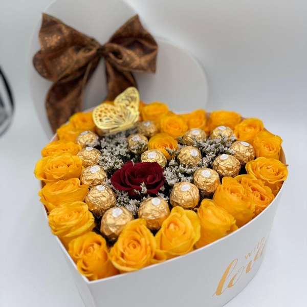 Heart-shaped box of yellow roses with chocolates and a red rose