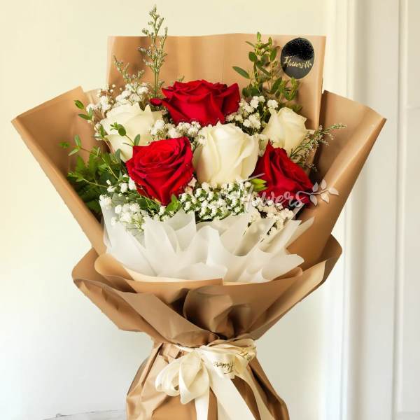 Bouquet of red and white roses wrapped in brown paper