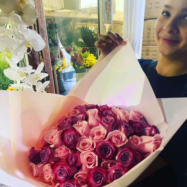 Large hand-tied bouquet of pink and purple roses wrapped in pale pink paper