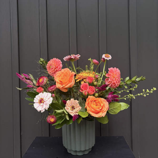 Mixed bouquet of orange and pink flowers in a ribbed vase