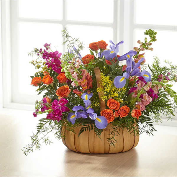 Basket arrangement of orange roses, purple irises, and pink flowers