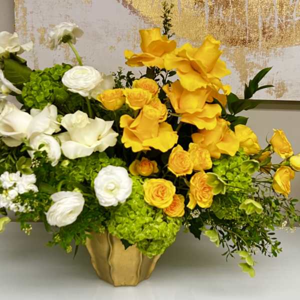 Yellow and white floral arrangement in a gold vase