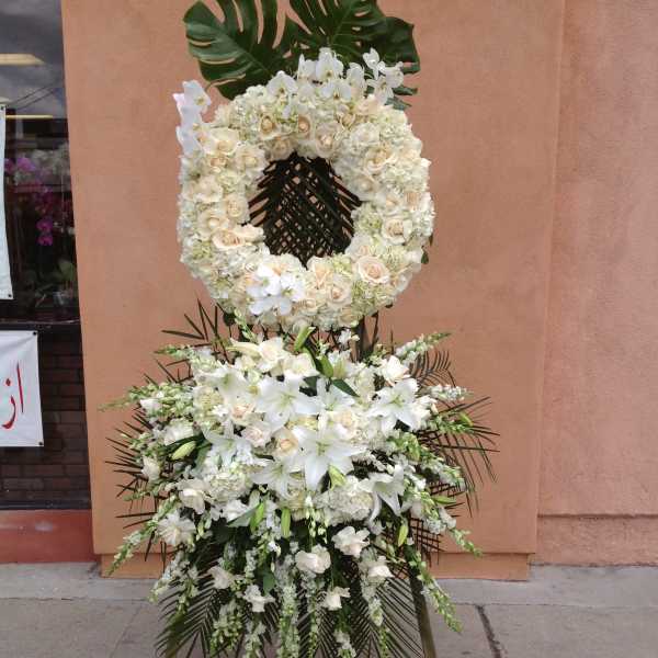 White floral funeral wreath and standing spray on an easel