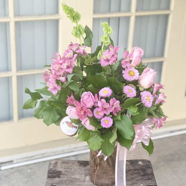 Pink roses and alstroemeria in a decorative vase with ribbon
