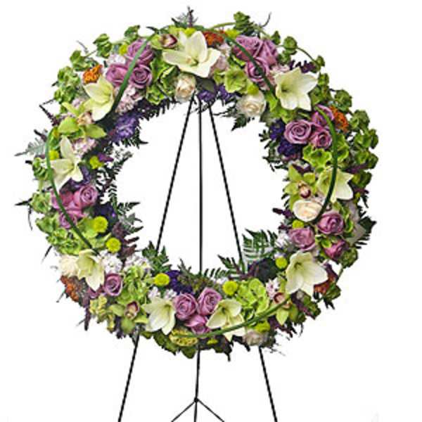 Floral wreath on a black easel with purple, white, and green blooms