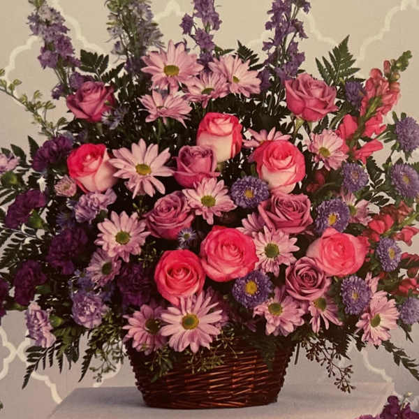 Pink roses and purple daisies in a wicker basket
