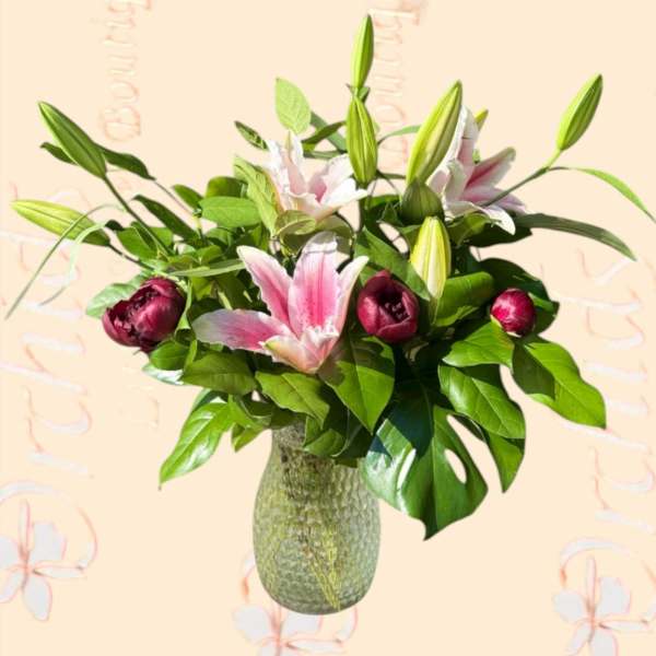 Pink lilies and dark pink tulips in a textured glass vase