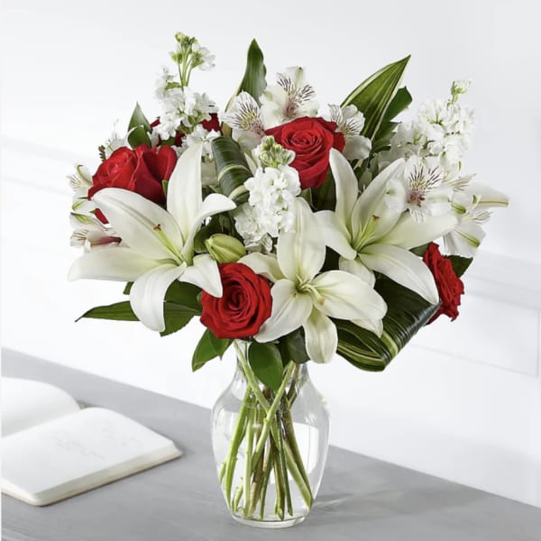 Red roses and white lilies arranged in a clear glass vase