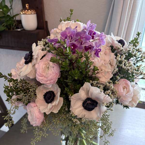 Bouquet of pale pink and purple flowers in a clear glass vase