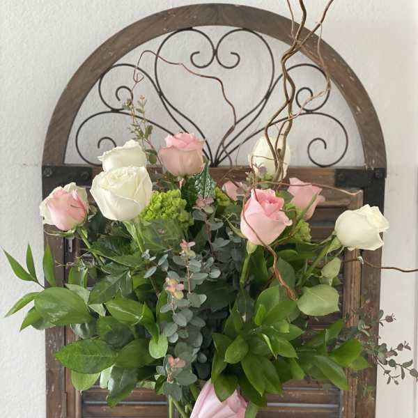 Pink and white roses in a glass vase with a pink ribbon