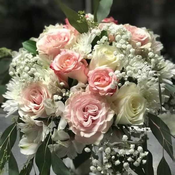 Bouquet of pink and white roses with baby's breath in a glass vase