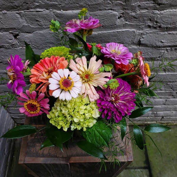Colorful mixed bouquet of zinnias and hydrangea in a rustic container