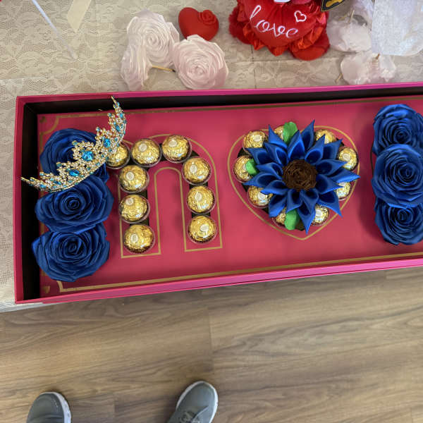 Decorative gift box with blue roses and chocolates arranged in letters