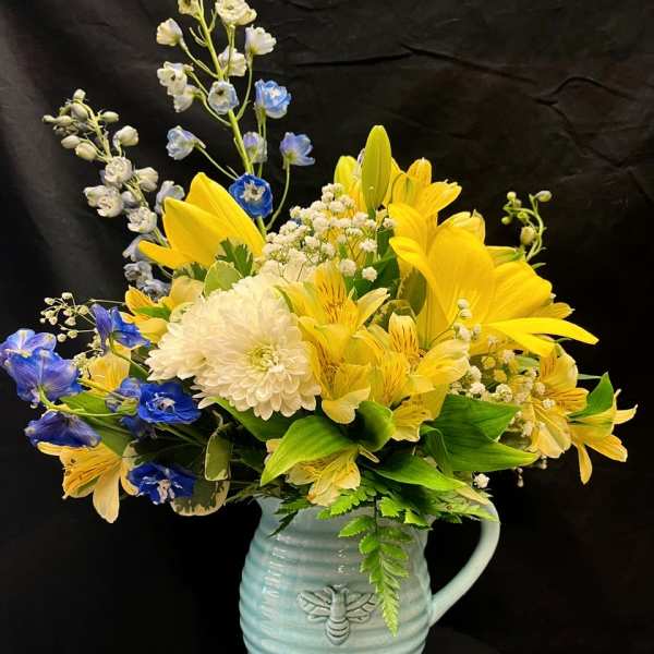 Yellow and blue mixed bouquet in a light blue ceramic pitcher
