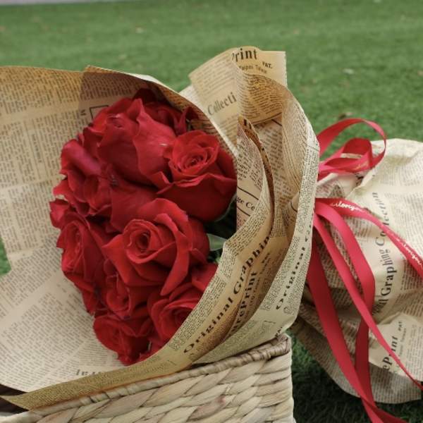Bouquet of red roses wrapped in newspaper-style paper with a red ribbon