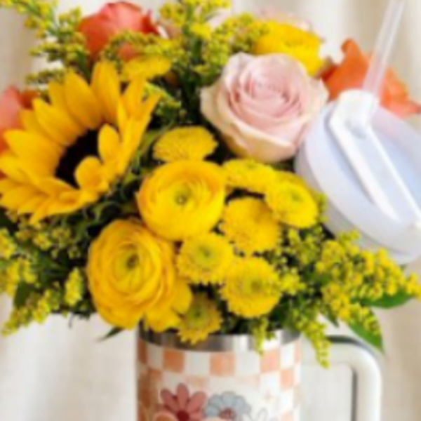 Bouquet of yellow and pink flowers in a decorative mug vase