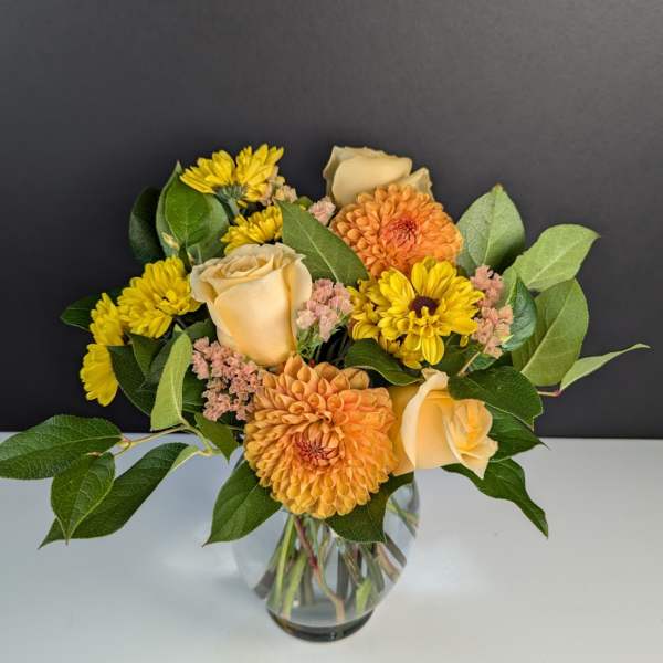 Bouquet of yellow and peach flowers in a clear glass vase