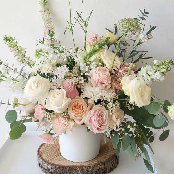 Pastel bouquet of roses, ranunculus, and white blooms in a white vase