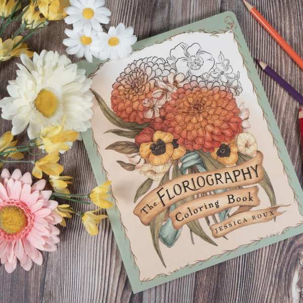 Coloring book with paper flowers and colored pencils on a wood surface