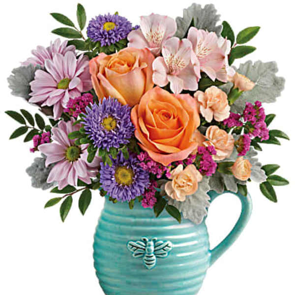 Bouquet of peach roses, pink daisies, and purple flowers in a turquoise pitcher vase