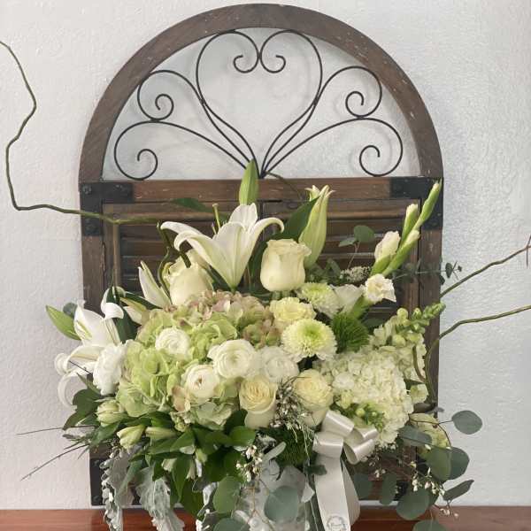 White floral arrangement in a white vase with lilies and roses