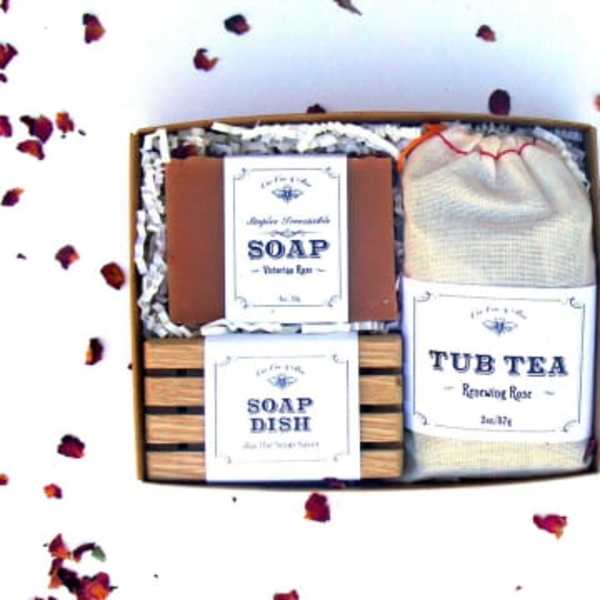 Gift box with soap, soap dish, and tub tea surrounded by rose petals