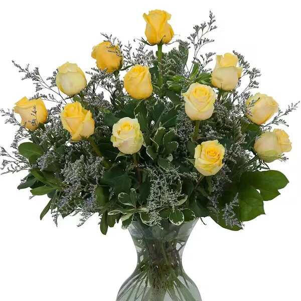 Yellow roses arranged in a clear glass vase with greenery