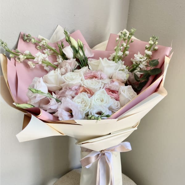Bouquet of white and blush roses wrapped in pink paper