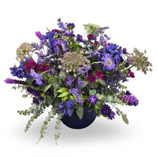 Purple and blue mixed flower arrangement in a dark vase