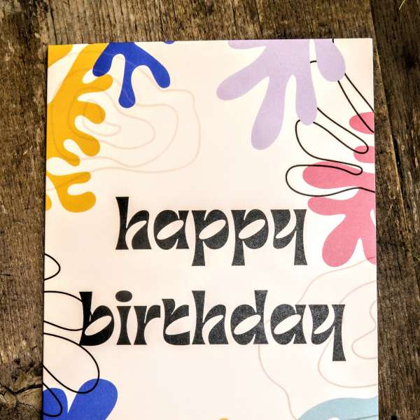 Birthday greeting card with black text and colorful abstract shapes on a white background