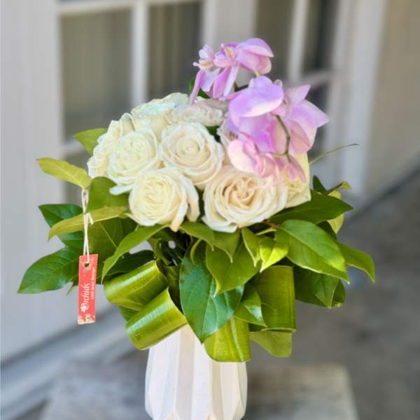 White roses and pink orchids in a white vase