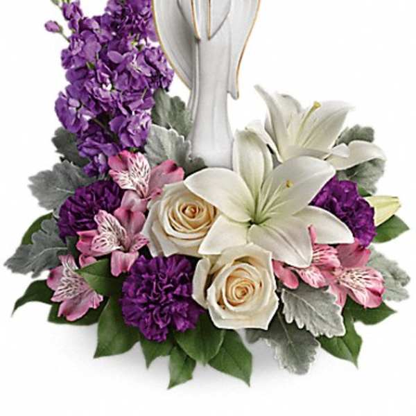 Purple and white floral arrangement with an angel figurine