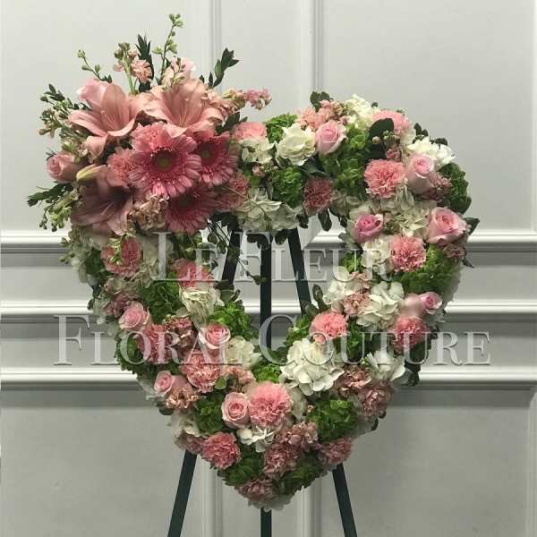 Heart-shaped floral wreath with pink and white flowers on an easel