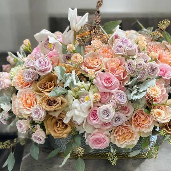 Large pastel bouquet of roses and orchids in a low container