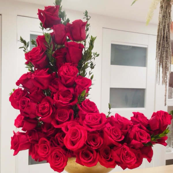 Large arrangement of red roses in a gold vase