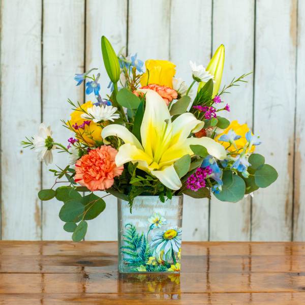 Mixed bouquet with lilies, carnations, and daisies in a painted glass vase