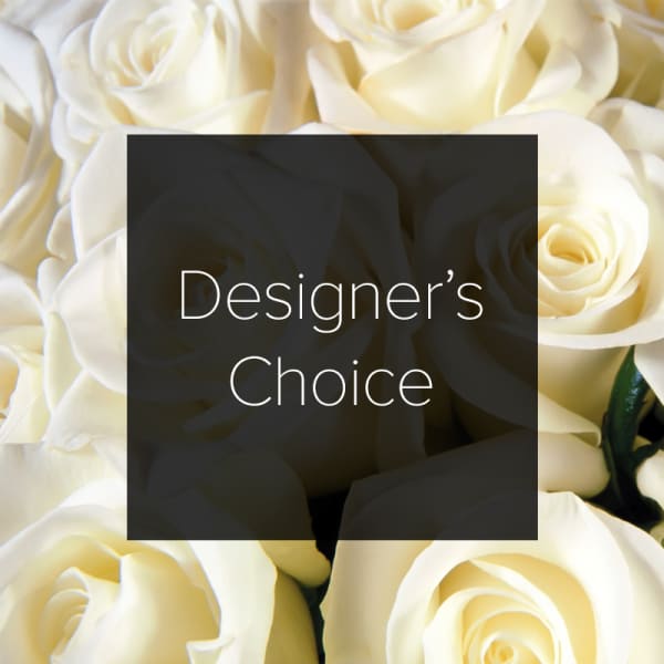 Cream-colored roses with a dark square label reading Designer's Choice