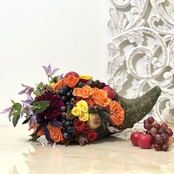 Horn-shaped floral arrangement with roses, grapes, and apples