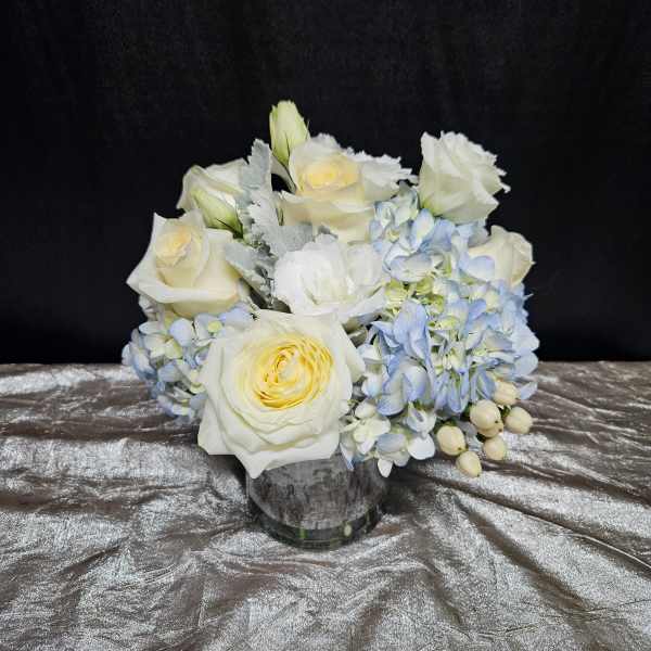 White roses and pale blue hydrangeas in a glass vase