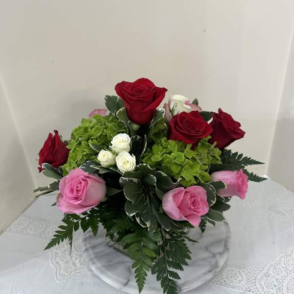 Bouquet of red and pink roses with green hydrangea in a glass vase