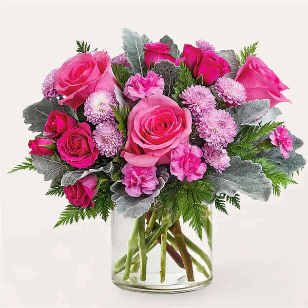 Pink roses and small pink flowers arranged in a clear glass vase