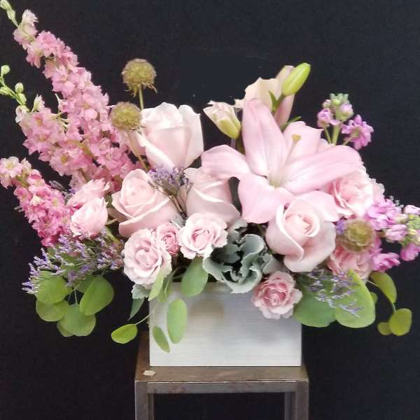 Pink lilies and roses arranged in a white box