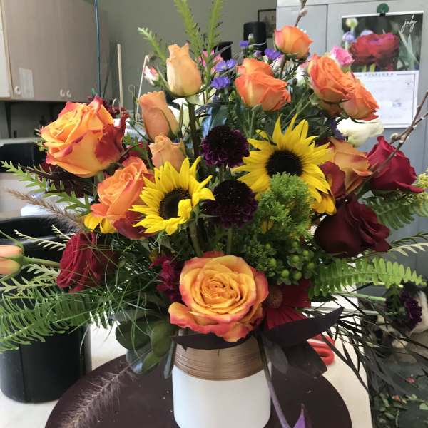 Mixed bouquet of orange roses and yellow sunflowers in a white vase