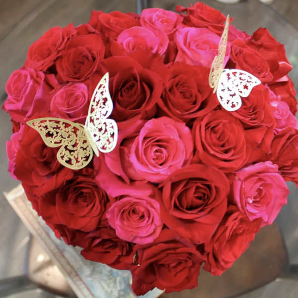 Heart-shaped bouquet of red and pink roses with butterfly picks