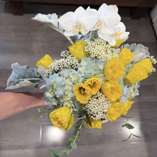 Bouquet of yellow tulips, white orchids, and pale blue hydrangeas